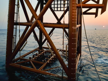 Close-up of metallic structure in sea against sky