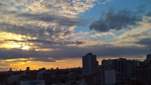 Buildings in city against cloudy sky during sunset