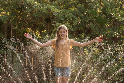 Girl plays in a sprinkler during summer