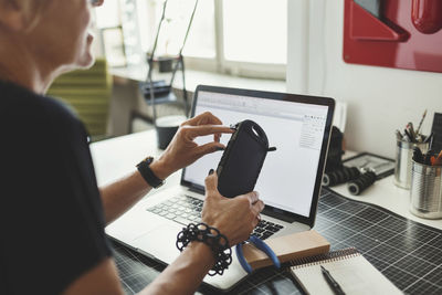 Midsection of industrial designer working on product at home office