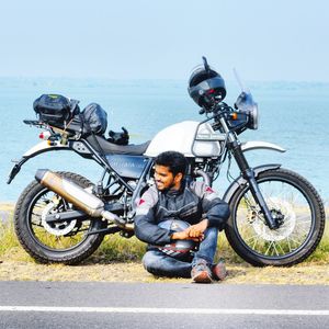 Man riding bicycle on road by sea