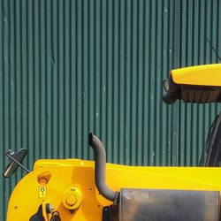 Yellow tractor against corrugated iron