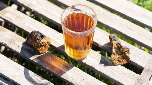 Organic chaga mushroom tea in a glass with pieces of natural birch mushroom on a wooden background.