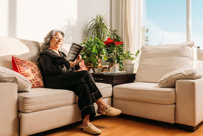 Young woman using digital tablet while sitting on sofa at home