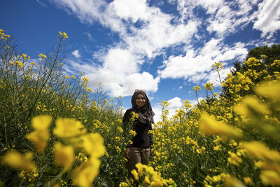 Smiling woman standing on field against sky