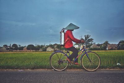 Side view of man riding bicycle on field