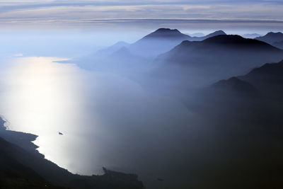 Foggy mist aerial silhouette of garda lake mountains at sunset, italy