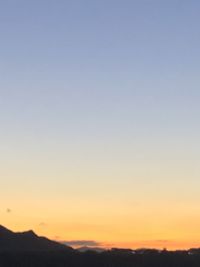 Scenic view of silhouette mountains against clear sky during sunset