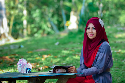 Portrait of young woman sitting on field