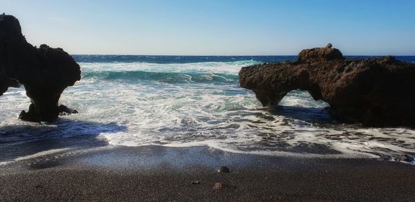 Rock formation on beach against sky