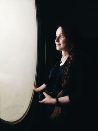 Woman looking through window in darkroom