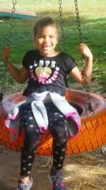 Portrait of smiling girl sitting on swing