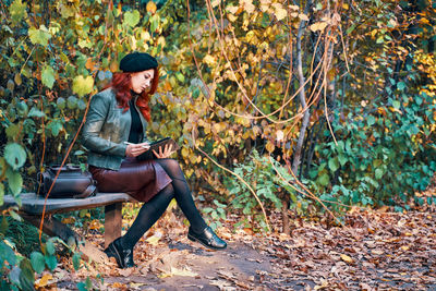 Young woman looking away while sitting on tree