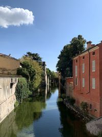 Buildings by river against sky