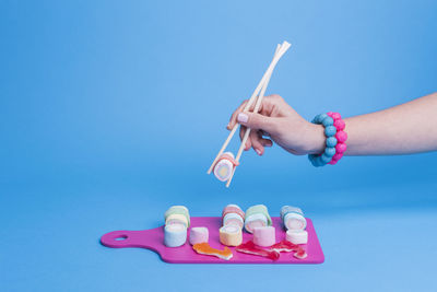 Female hand using chopsticks with candy sushi