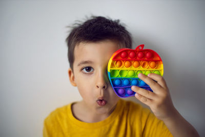 Boy in a yellow t-shirt plays a fashion game pop it in the form of a silicone apple