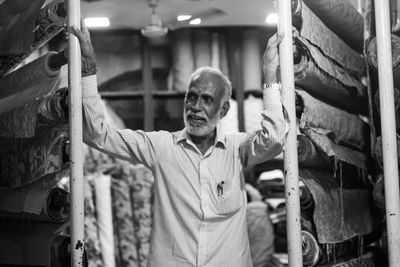 Man looking away while standing by fabric in store