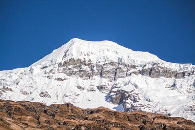 Scenic view of snowcapped mountains against clear blue sky