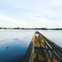 Wooden pier over lake against sky