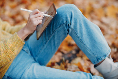 Low section of man sitting against blue wall