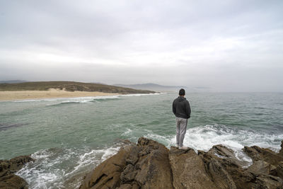 Rear view of man looking at sea against sky