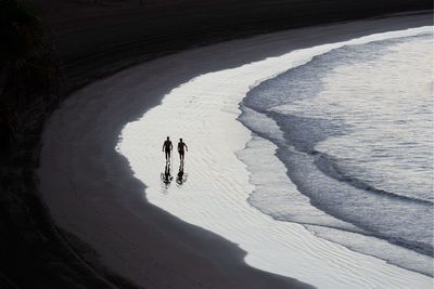 High angle view of friends walking at beach during sunset