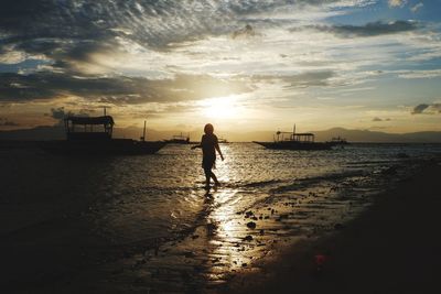 Silhouette man standing on beach against sky during sunset