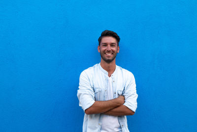 Portrait of young man standing against blue wall