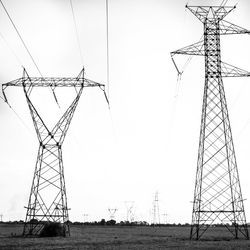 Low angle view of electricity pylon on field