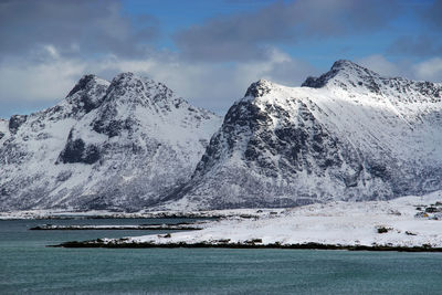 Scenic view of sea by snowcapped mountain against sky