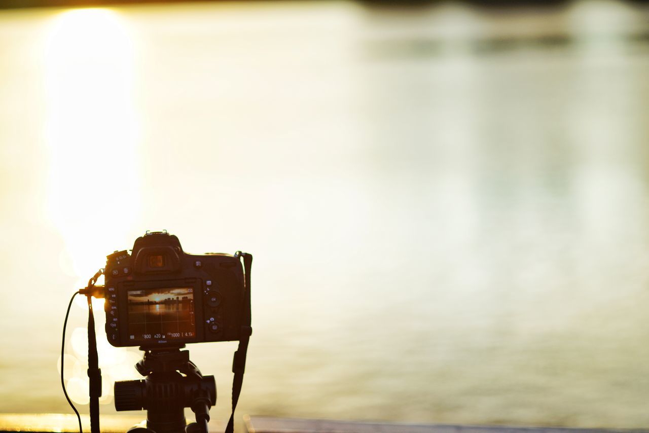 REFLECTION OF CAMERA ON WATER AGAINST SKY