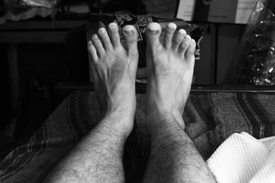 Low section of man relaxing on bed at home