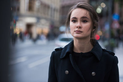 Young woman looking away while standing outdoors