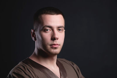 Portrait of young man against black background