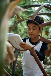 Close-up of boy holding camera while standing outdoors