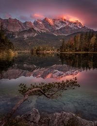 Scenic view of lake by mountains against sky during sunset