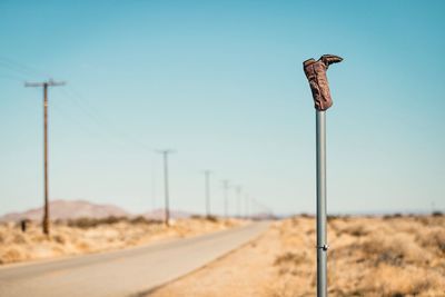 Boot on pole at roadside against blue sky