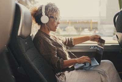 Side view of woman using mobile phone while sitting in car