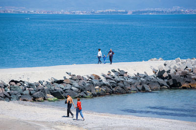 Men standing on rock at beach