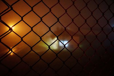 Full frame shot of chainlink fence against sky during sunset