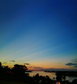 Silhouette trees against blue sky during sunset