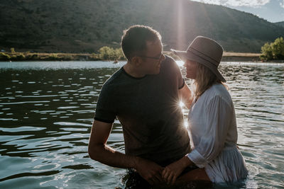 Man and woman standing in a lake smiling and talking on a sunny day