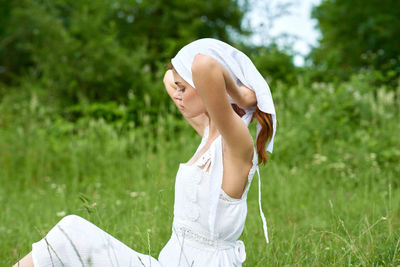 Side view of woman sitting on field