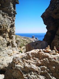 Rock formations by sea against clear blue sky