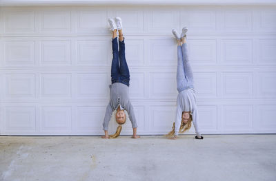 Girls doing handstand in front of garage door