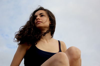 Portrait of beautiful young woman looking away against sky