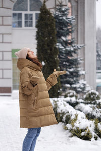 Happy middle age woman catching snowflakes in the city outdoors. relaxed emotional person walking in