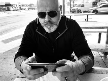 Midsection of man holding sunglasses while sitting outdoors