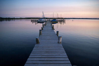 Wooden pier in lake at sunset