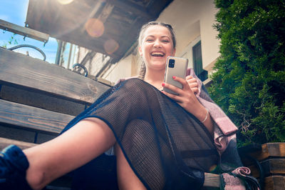 Young smiling woman using smartphone in cafe outdoor